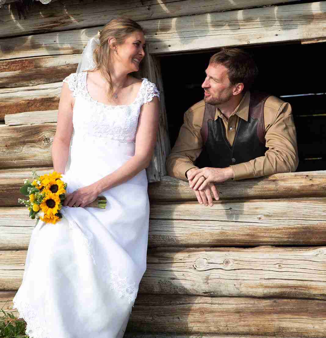 a couple smiling in wedding attire in a cabin