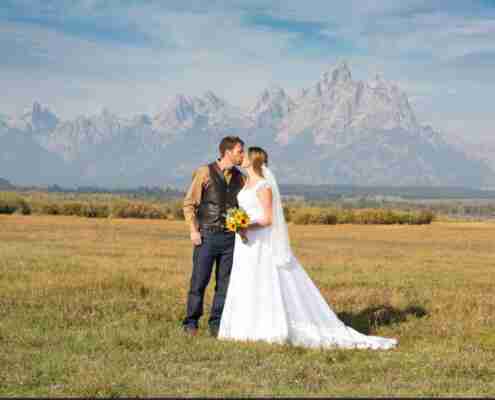a bride and groom kissing outside in a field