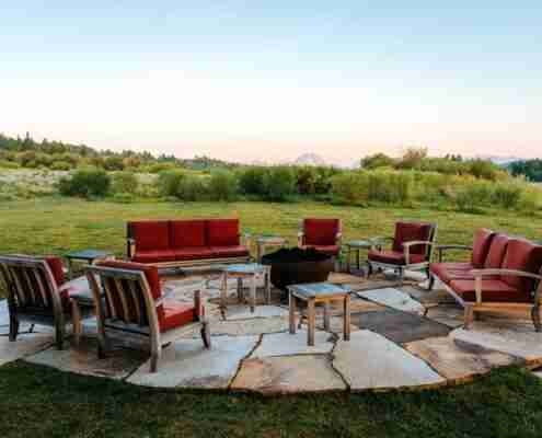 an outdoor patio area with firepit and lounge chairs in a field
