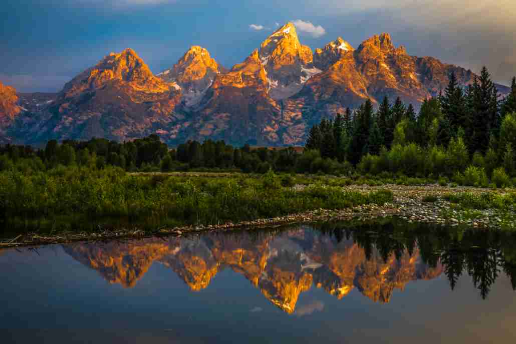 The dramatic colors of the Grand Teton Mountains reflecting in the water on a clear summer morning.